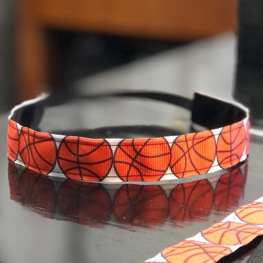 basketball headband with large orange basketballs on a grosgrain ribbon and black velvet on the backside.  There is a thin band of elastic towards the back to be worn at the backside of your head