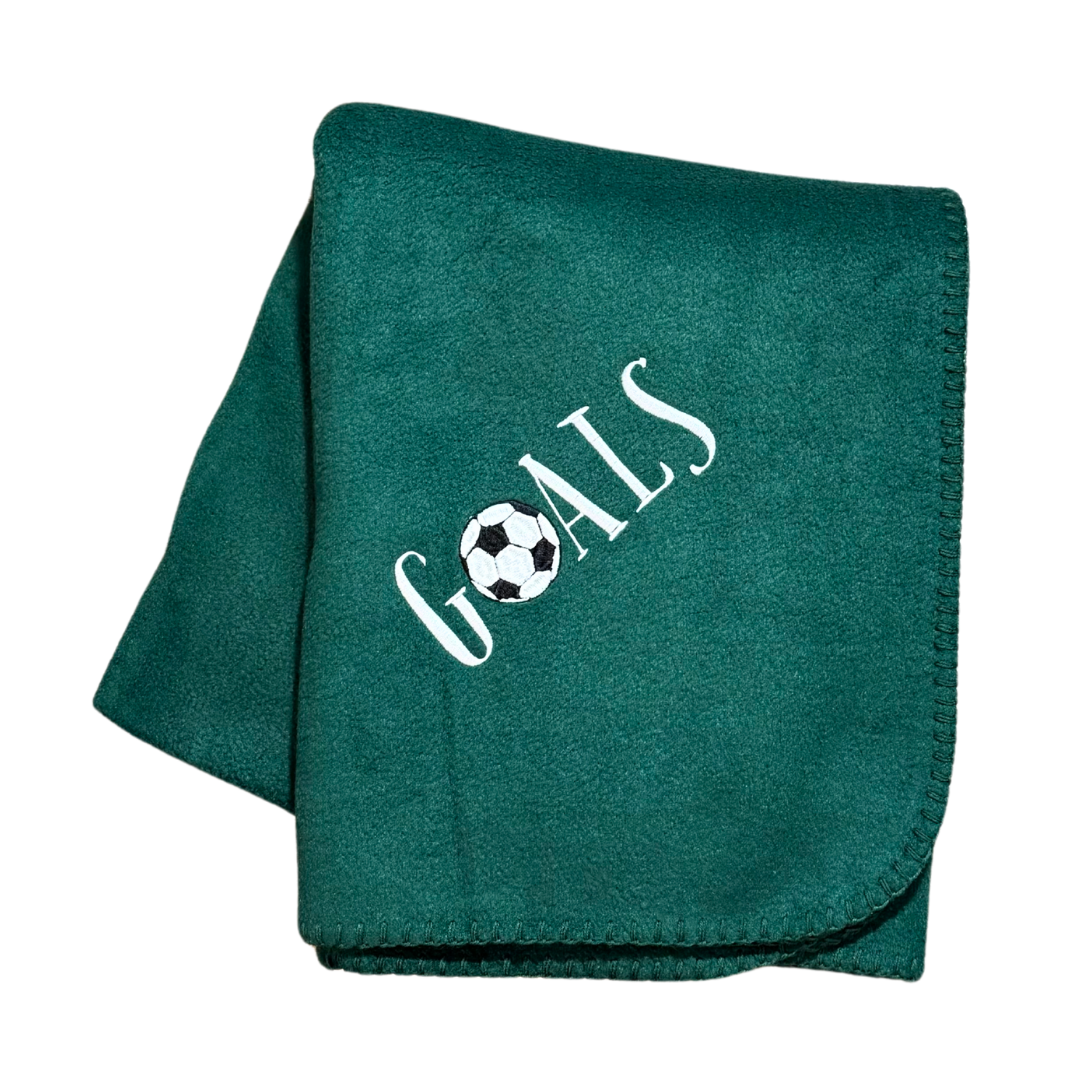 Green blanket with 'GOALS' and a soccer ball design in white stitching