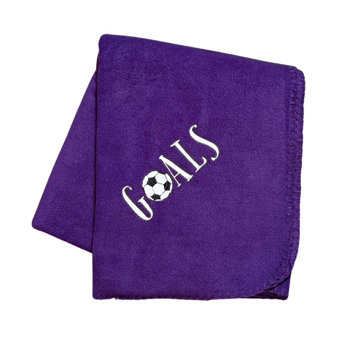 Purple blanket with 'GOALS' and a soccer ball design in white stitching