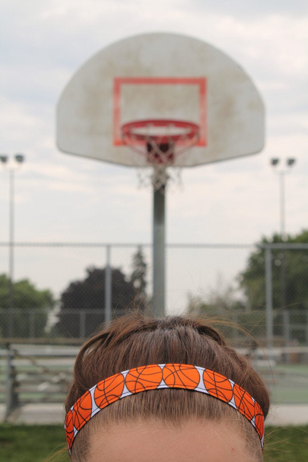 basketball headband on model standing in front of a basketball hoop