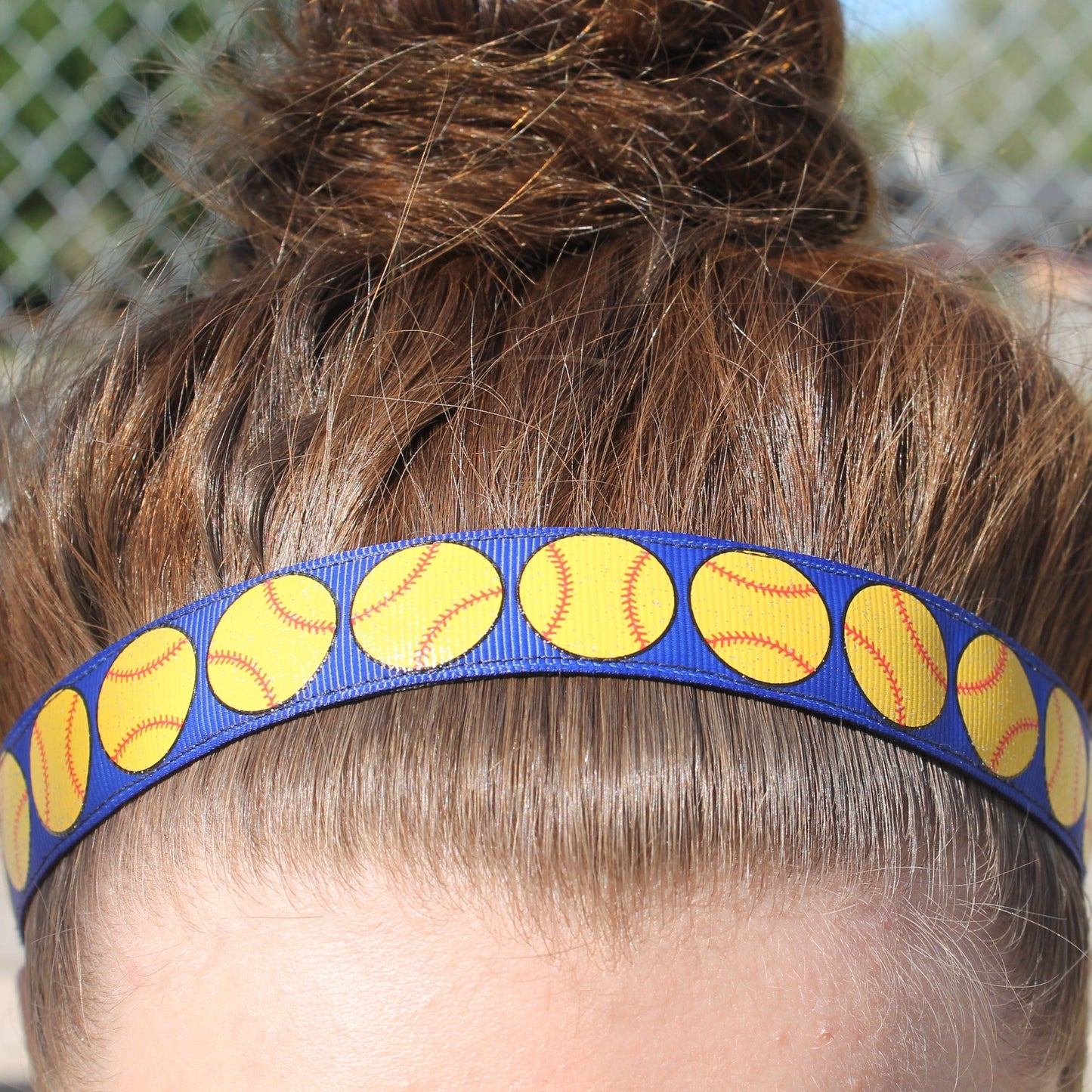 blue softball headband on girl with hair in a bun