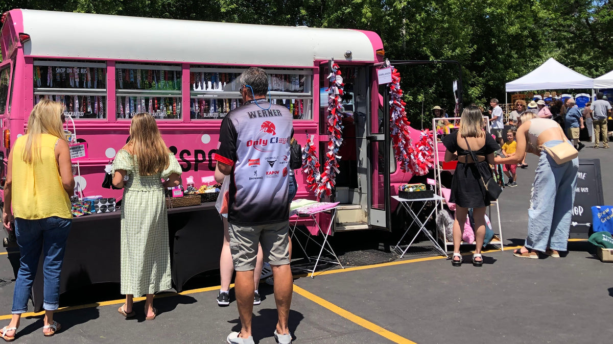 customers shopping outside of Sporty Girl Accessories pink bus mobile boutique