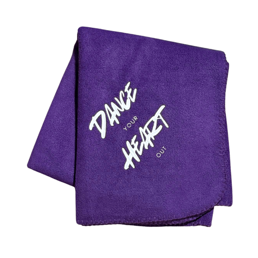 purple fleece blanket that has "dance your heart out" embroidered in white stitching