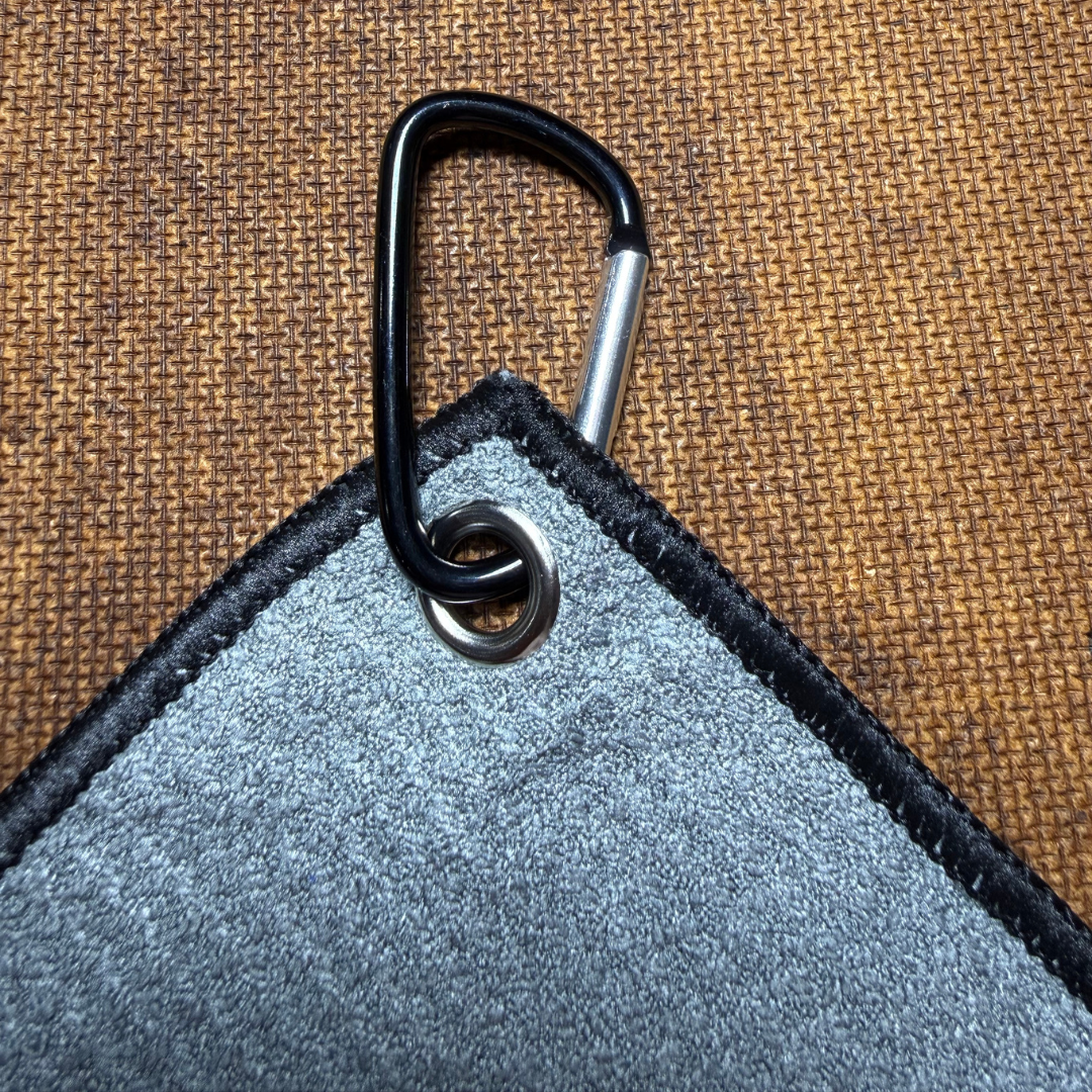 Gray microfiber towel with a black carabiner on a brown textured background