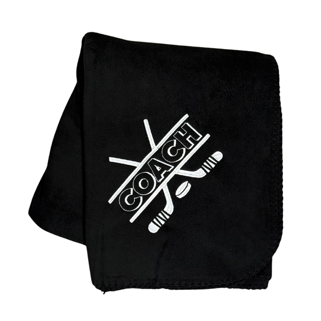 Black fleece blanket with 'COACH' and hockey stick design in white stitching