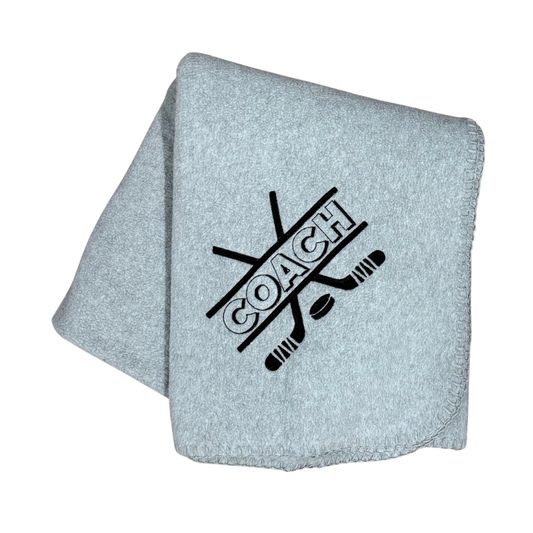 Gray blanket with 'COACH' and hockey stick design in black embroidery