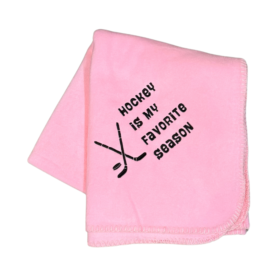 Pink blanket with 'Hockey is my favorite season' text and hockey stick graphic in black embroidery thread