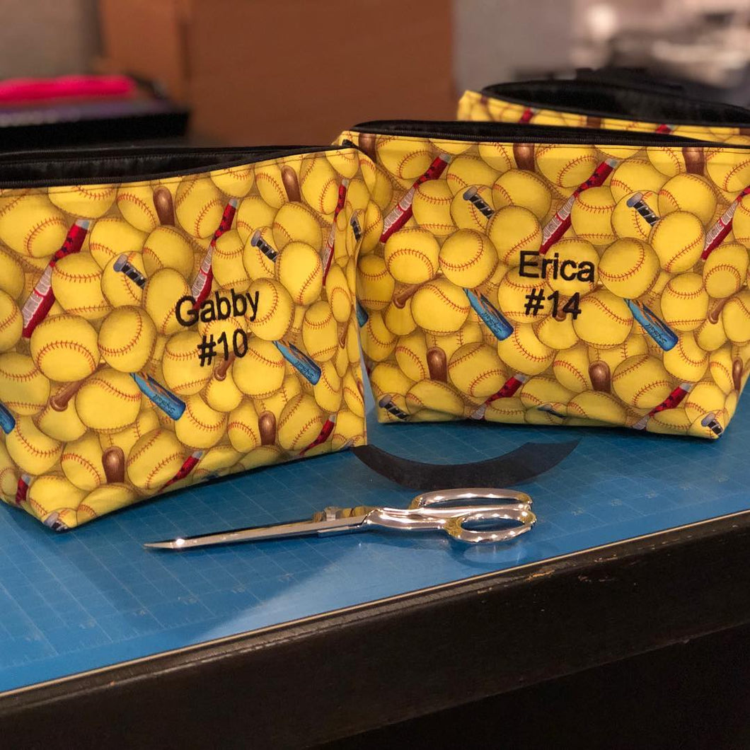 two yellow softball makeup bags with embroidered names Gabby #10 and Erica #14 in the center