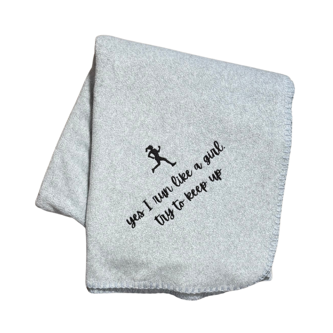 gray running blanket with running girl and text in black embroidery