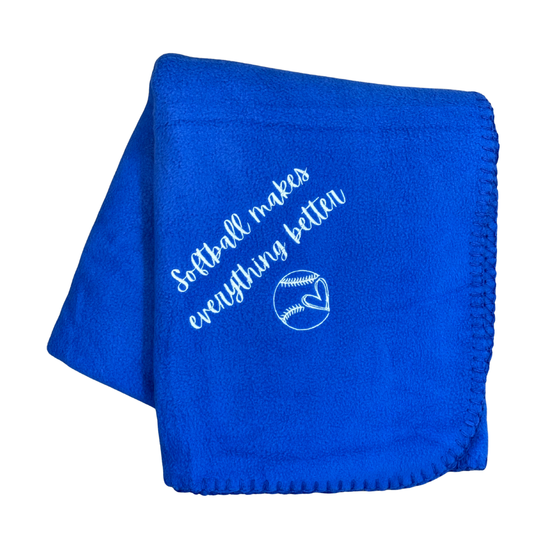 Blue blanket with 'Softball makes everything better' text and a softball graphic in white embroidery