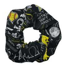 Load image into Gallery viewer, black softball scrunchie with softball words and pictures in white and yellow
