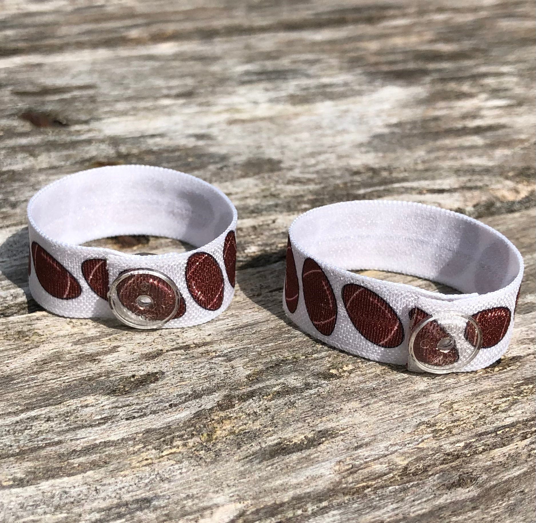 set of two white sleeve clips with brown footballs and clear snaps