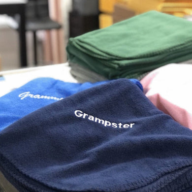 personalized fleece blankets one royal blue blanket with Grammy embroidered in white and one navy blue blanket with Grampster embroidered in white thread